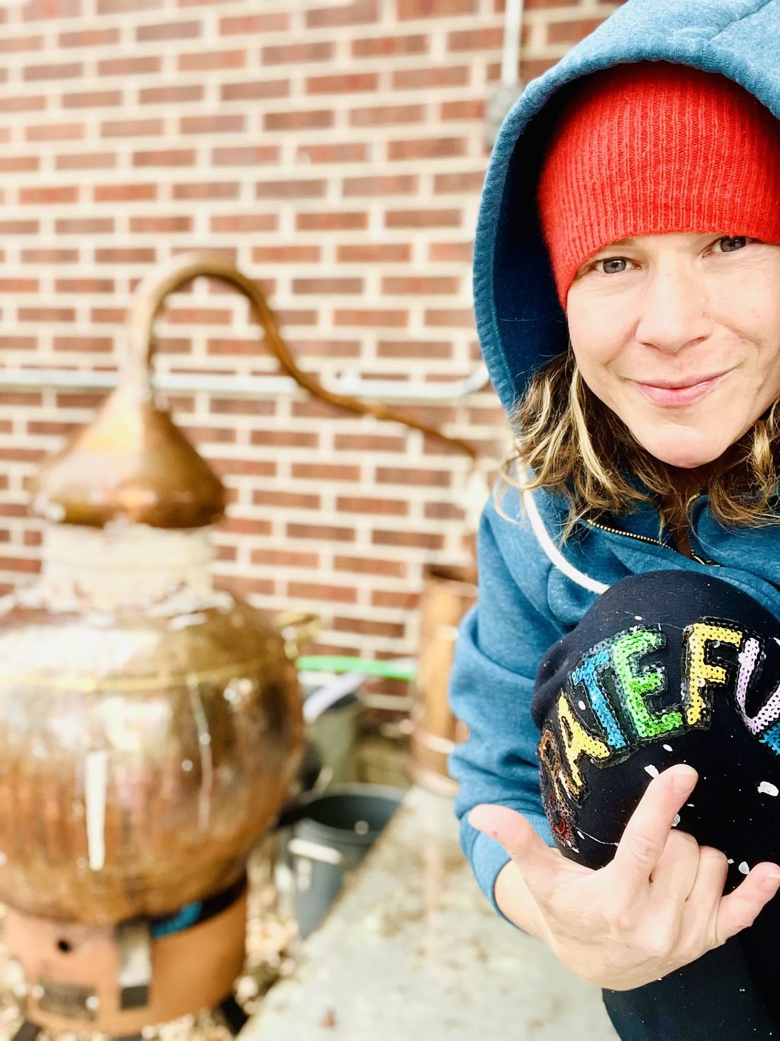 Blair beside a copper spagyric still, distilling plant medicine for Apothecary N' Bliss